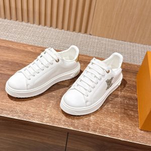 White low-top sneakers photographed on a warm wood tabletop