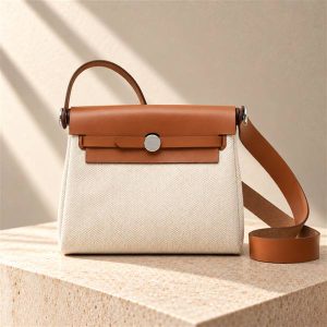 Hermès Herbag style handbag on a warm ivory limestone surface